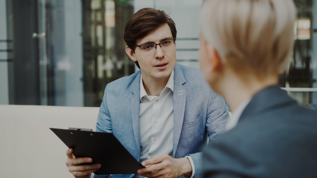 why-choose-us HR manager with clipbooard interviewing young female candidate for hiring on vacant position sitting on sofa in modern office indoors